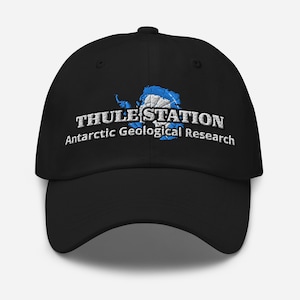 May include: Black baseball cap with the text "THULE STATION Antarctic Geological Research" in white. The design includes a blue and white graphic of Antarctica. The cap is a classic six-panel design with a curved brim.
