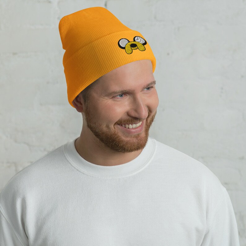May include: A yellow beanie with a black and white embroidered cartoon dog face.