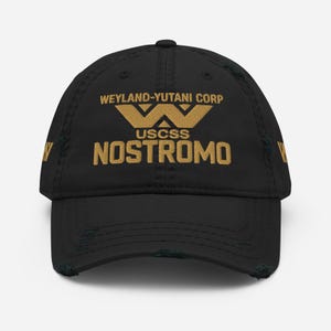 Puede incluir: Gorra de béisbol negra desgastada con texto dorado. La gorra presenta el texto "WEYLAND-YUTANI CORP" encima de un logotipo "W" estilizado y "USCSS NOSTROMO" debajo. La gorra tiene un aspecto desgastado con bordes deshilachados.