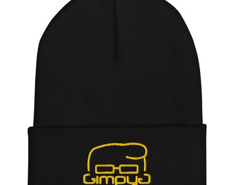 May include: Black beanie with a yellow embroidered design. The design features a stylized face with glasses and the word "Gimpyo" below. The beanie is made of a soft, knitted material.
