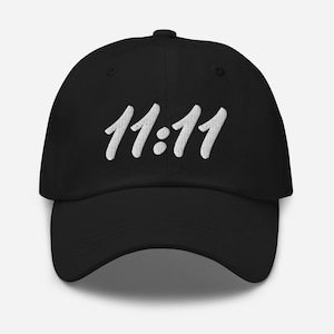 Peut inclure: Une casquette de baseball noire avec un motif brodé blanc qui dit "11:11".