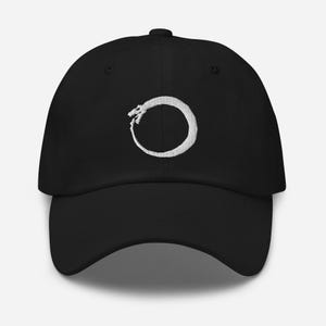 May include: A black baseball cap featuring a white embroidered ouroboros symbol. The ouroboros is a snake biting its own tail, representing eternity and the cyclical nature of life.