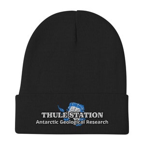 以下が含まれることがあります： 「THULE STATION 南極地質調査」と刺繍された白と青のロゴが付いた黒いニットビーニー。