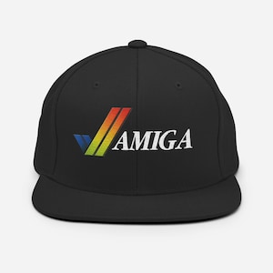 May include: Black snapback hat featuring the word "AMIGA" in white, with a colorful logo. The logo includes a blue, yellow, and red design. The hat has a flat brim and a structured crown.