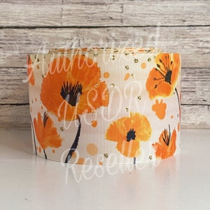 May include: A roll of white ribbon with a repeating pattern of orange watercolor poppies and gold glitter.