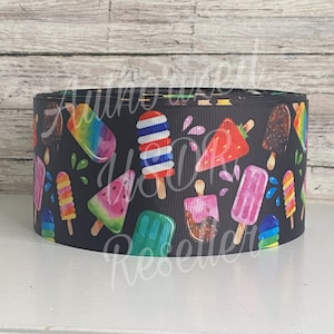 May include: A black ribbon with a colorful print of various popsicles. The popsicles are in different shapes and flavors, including watermelon, strawberry, and chocolate.