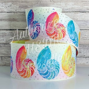 May include: White ribbon featuring colorful watercolor nautilus shell designs in shades of blue, orange, yellow, and pink. The ribbon is embellished with silver glitter dots, adding a touch of sparkle. Perfect for crafting and embellishments.