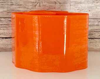 May include: Orange plastic flower pot with a scalloped edge.