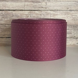 May include: A roll of burgundy grosgrain ribbon with white polka dots.