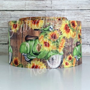 May include: A green vintage scooter with sunflowers and a woodgrain background. The scooter is surrounded by sunflowers and has a brown wooden background.