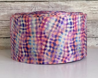 May include: A roll of purple, pink, orange, and blue patterned ribbon. The ribbon has a checkered pattern with a tie-dye effect.