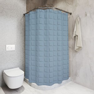 May include: A blue shower curtain with a geometric pattern of squares. The curtain is hung on a curved shower rod.