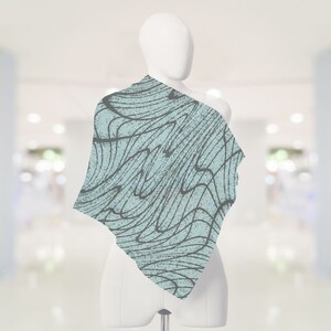 May include: A light blue scarf with a black and white abstract pattern. The pattern resembles waves or lines.
