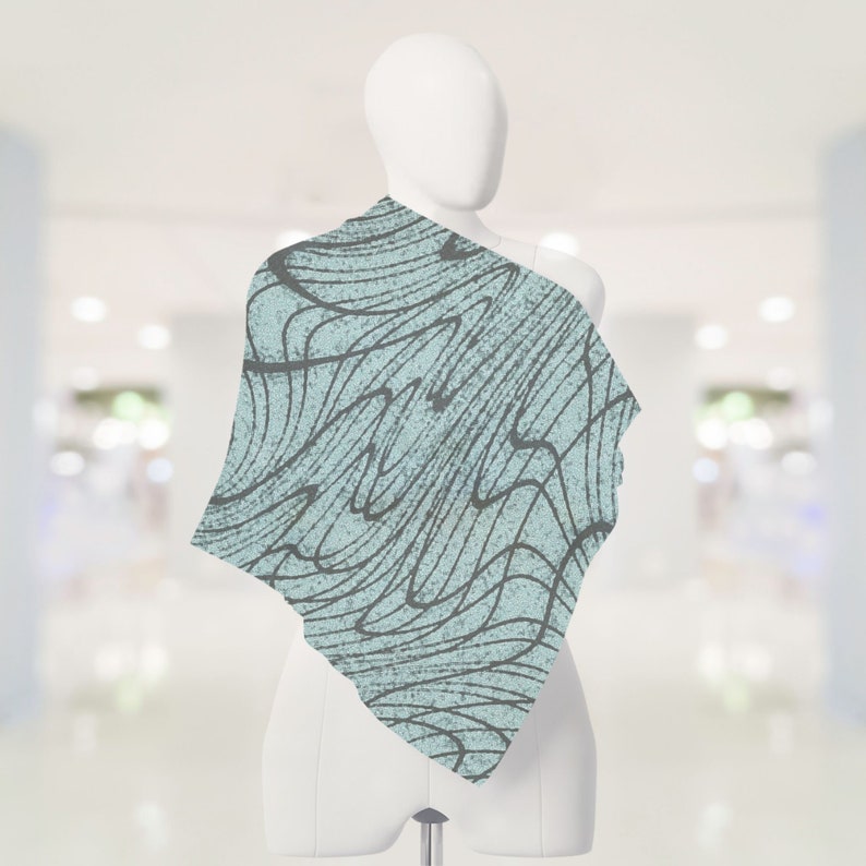 May include: A light blue scarf with a black and white abstract pattern. The pattern resembles waves or lines.