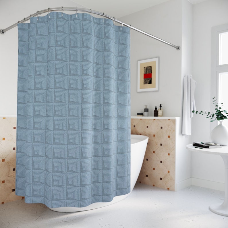 May include: A blue shower curtain with a geometric pattern of squares. The curtain is hanging in a bathroom with a white tub and tiled walls.