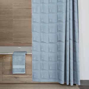 May include: A light blue shower curtain with a geometric pattern of squares. The curtain is hanging in a bathroom with a wooden bathtub and a towel on the edge of the tub.