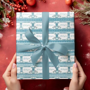 May include: A blue and white gift wrap with a snowman design and the text "Let it snow" repeated across the paper. The gift is tied with a blue ribbon.