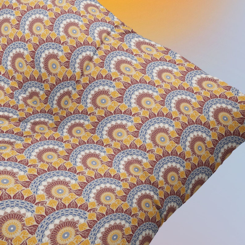 May include: A decorative pillow with a repeating pattern of yellow, blue, and red mandala-like designs. The pillow is made of a soft, textured fabric.
