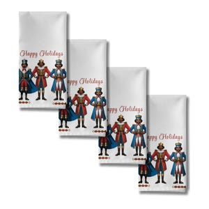 May include: Four white decorative towels with a festive design. Each towel features a line of nutcracker figures in red, blue, and gold uniforms. The words "Happy Holidays" are printed in red script across the top of each towel.