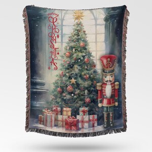 Puede incluir: Manta navideña tejida con un diseño festivo. Presenta un árbol de Navidad decorado, regalos y un soldado de juguete. Las palabras "Merry Christmas" están escritas verticalmente en rojo. La manta tiene un borde con flecos.