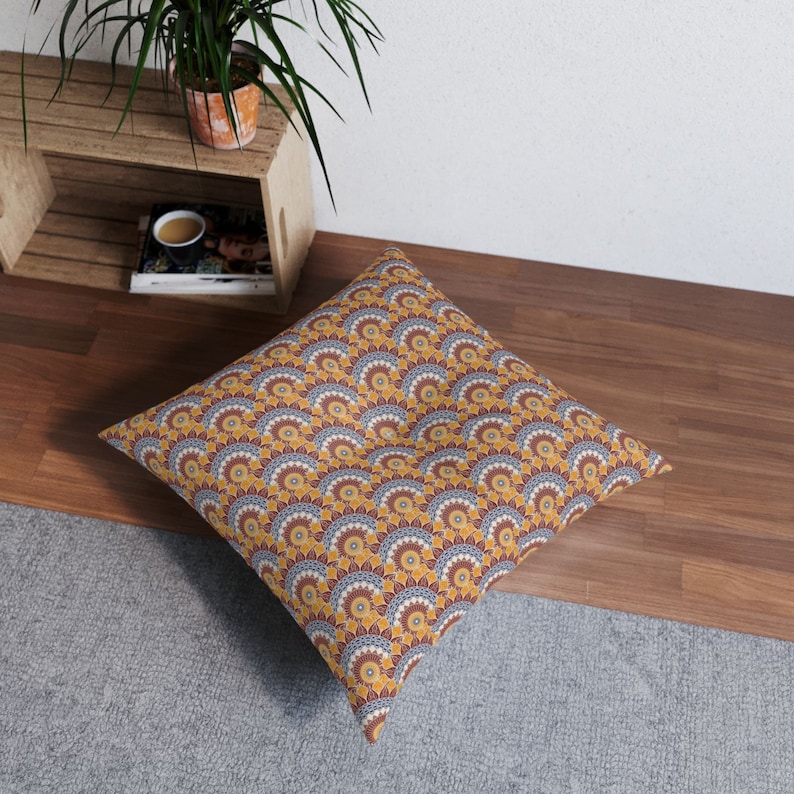 May include: A large floor cushion with a geometric pattern in shades of yellow, orange, red, and blue. The pattern is made up of repeating circles and arches.