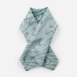 May include: A light blue scarf with a black and white abstract pattern. The scarf is folded in half and tied in a knot.