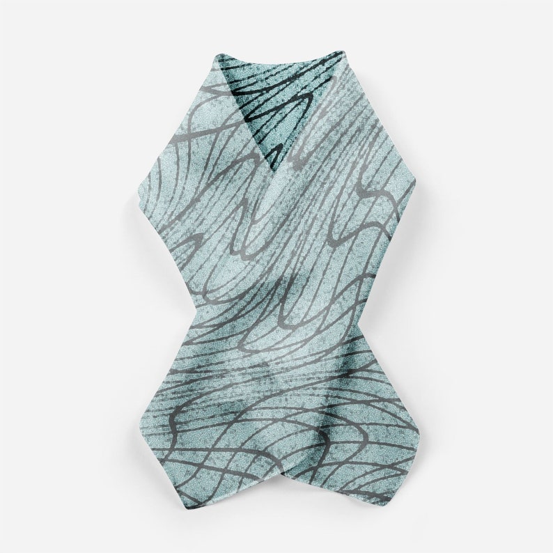 May include: A light blue scarf with a black and white abstract pattern. The scarf is folded in half and tied in a knot.