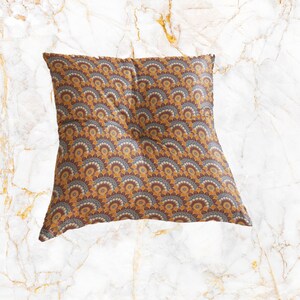 May include: A brown and yellow patterned throw pillow with a geometric design. The pillow is made of a soft, plush fabric and has a square shape.