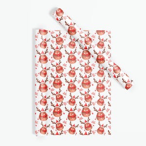 Op de afbeelding: Wit cadeaupapier met een herhalend patroon van cartoon rendieren met rode sjaals en kerstmutsen. De rendieren hebben bruine geweien en zijn omringd door rode zuurstokken. Een rol bijpassend papier is zichtbaar.
