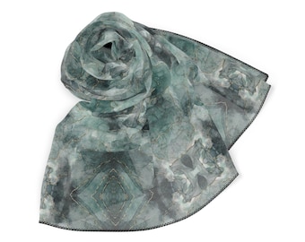 May include: A green and gold patterned silk scarf with a black trim. The scarf is folded and tied in a knot.