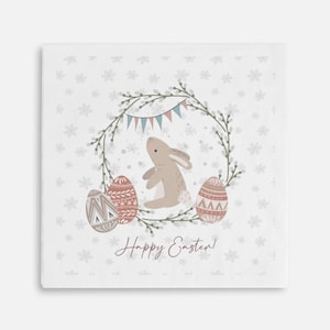 May include: A white card with a light brown bunny sitting in a wreath of green leaves with pink and blue Easter eggs and a banner that says "Happy Easter!" The background is a white pattern of small flowers.