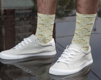 May include: A pair of white canvas sneakers with a fish pattern on the socks. The socks are a light yellow with a brown fish pattern.