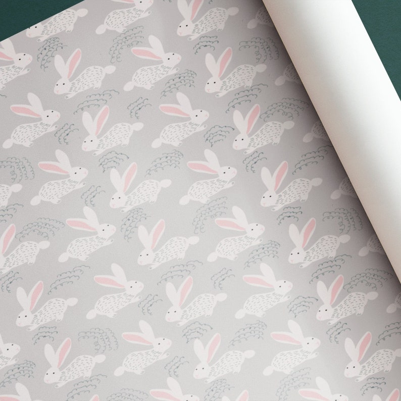 May include: A repeating pattern of white bunnies with pink ears on a light gray background. The bunnies are running and have a textured, fuzzy appearance. The background has a subtle pattern of gray lines.