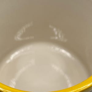Puede incluir: Una taza de cer&aacute;mica con interior color crema y borde amarillo brillante. El interior tiene marcas sutiles de color claro. El dise&ntilde;o de la taza es simple y limpio, con un enfoque en el contraste de los colores.