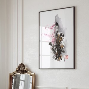 May include: Framed art print featuring a watercolor illustration of a samurai warrior with a sword, accented by pink cherry blossoms. The artwork is in a black frame and hangs on a white wall. The overall aesthetic is minimalist and elegant.