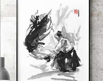May include: A framed sumi-e ink painting depicting a martial artist in a white gi and black hakama. The artwork shows a dynamic action scene with a dark, abstract shape. A red seal is visible in the upper right corner of the artwork.
