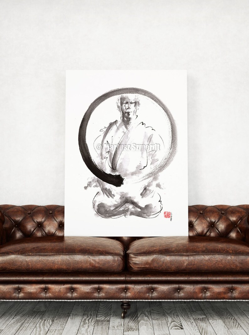 May include: A black and white ink painting of a person in a seated meditation pose, framed by a large black circle. The artwork is on a white canvas, with a red stamp in the lower right corner. The canvas is displayed above a brown leather couch.