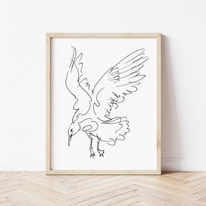 May include: A framed art print featuring a minimalist black line drawing of a seagull in flight. The bird is depicted with outstretched wings and a downward gaze, set against a white background. The frame is a light wood color.