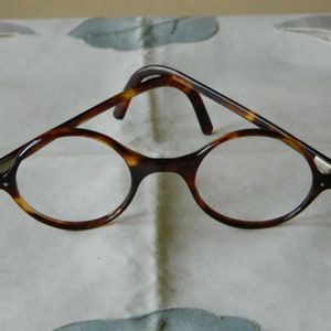 May include: A pair of tortoiseshell round eyeglasses with silver accents.