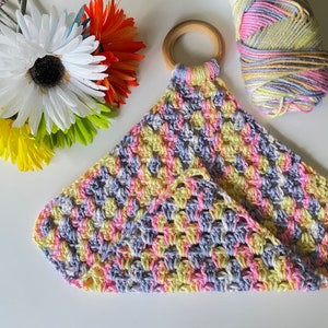May include: A crocheted baby mobile with a wooden ring, featuring a multi-colored design of pink, yellow, and purple yarn.