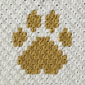 May include: A white crocheted blanket with a large golden brown paw print in the center.