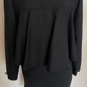 May include: A black blazer with a ruffled hem and long sleeves. The blazer has a simple, elegant design.