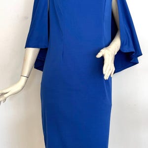 May include: A royal blue dress with a high collar and a cape-like sleeve detail.