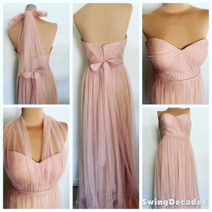 May include: A blush pink tulle bridesmaid dress with a sweetheart neckline and a bow at the back. The dress has a halter strap option and can be worn with or without a veil.