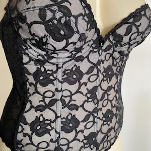 May include: Black lace corset with a sweetheart neckline and boning. The corset has a floral pattern and is made of a sheer fabric.