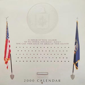 May include: A 2000 calendar with the text "IN HONOR OF THOSE MEMBERS OF THE CENTRAL INTELLIGENCE AGENCY WHO GAVE THEIR LIVES IN THE SERVICE OF THEIR COUNTRY." The image includes the American flag and a flag with the CIA logo.