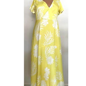 May include: A yellow maxi dress with a white floral print. The dress has a V-neckline and short sleeves.
