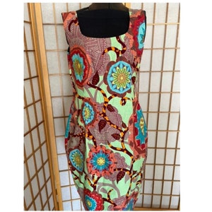 May include: A sleeveless dress with a green background and a colorful floral print. The flowers are red, orange, blue, and yellow. The dress has a square neckline.