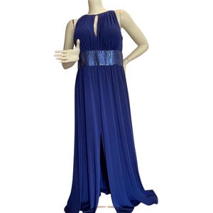 May include: A long, navy blue gown with a high neckline and a keyhole detail. The dress features a sequined belt and a thigh-high slit. The dress is displayed on a mannequin.