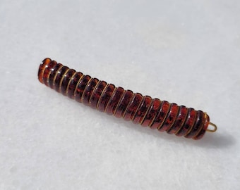 Peut inclure: Une pince à cheveux marron composée de pièces rondes translucides empilées avec un fil doré traversant le centre.
